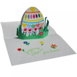 Préparation d'une jolie carte pop-up d'un ?uf de Pâque décoré de gommettes placé dans l'herbe du jardin . Un bricolage papier en 3D pour la décoration de la maison.