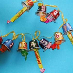 Réaliser une guirlande pour attendre Noël en comptant les jours de décembre. Cette guirlande calendrier est réalisée avec des capsules à café évidées, numerot