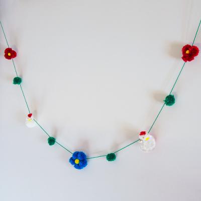 Une guirlande de laine avec des poules et des fleurs en pompons